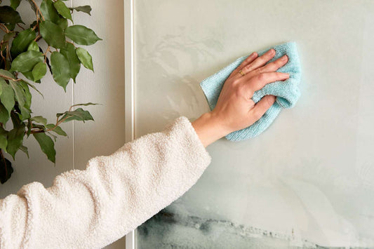 human hand wiping surface with blue microfibre cloth